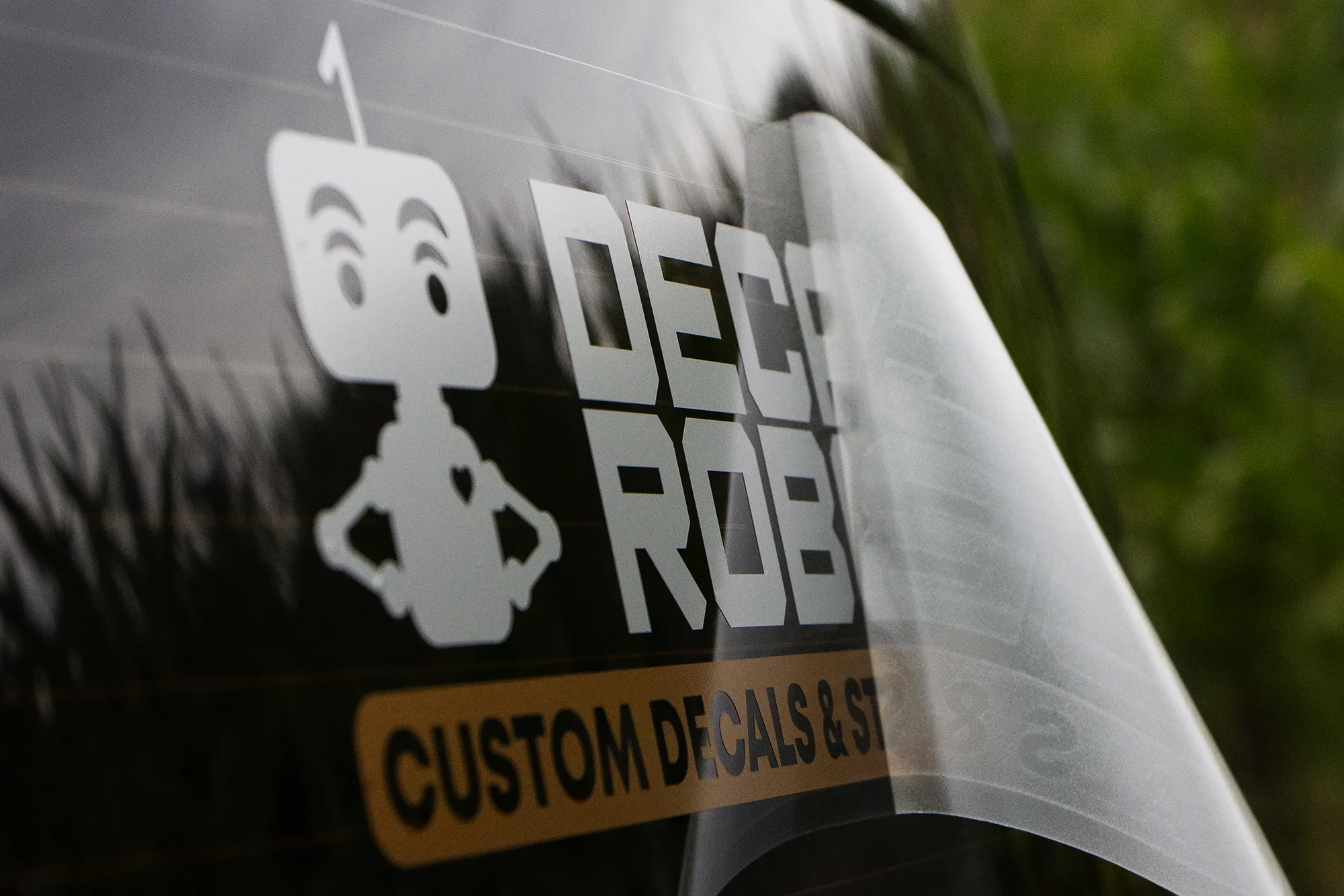 Vinyl decal of Decal Robot logo being applied to a windshield.